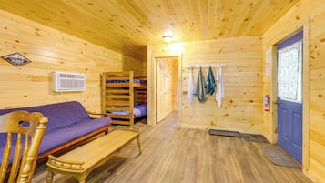 A wooden cabin interior with a bunk bed, a sofa, a bench, and a door.