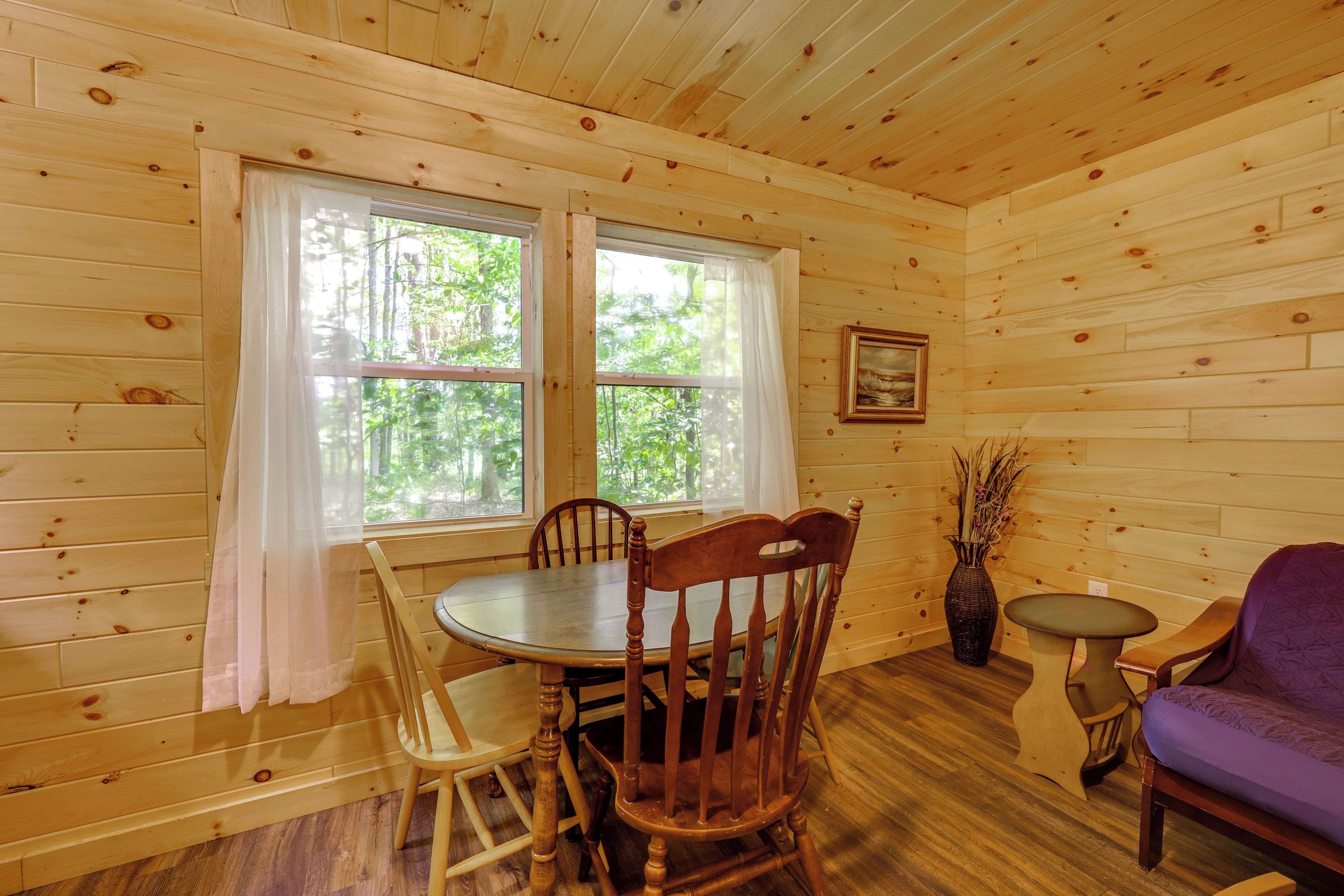 A wooden interior with a dining table, chairs, a sofa, and a small side table.