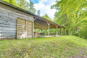 A rustic wooden cabin with a covered porch and picnic tables.