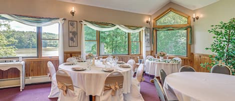 A banquet hall with round tables, white tablecloths, and chairs with beige sashes.