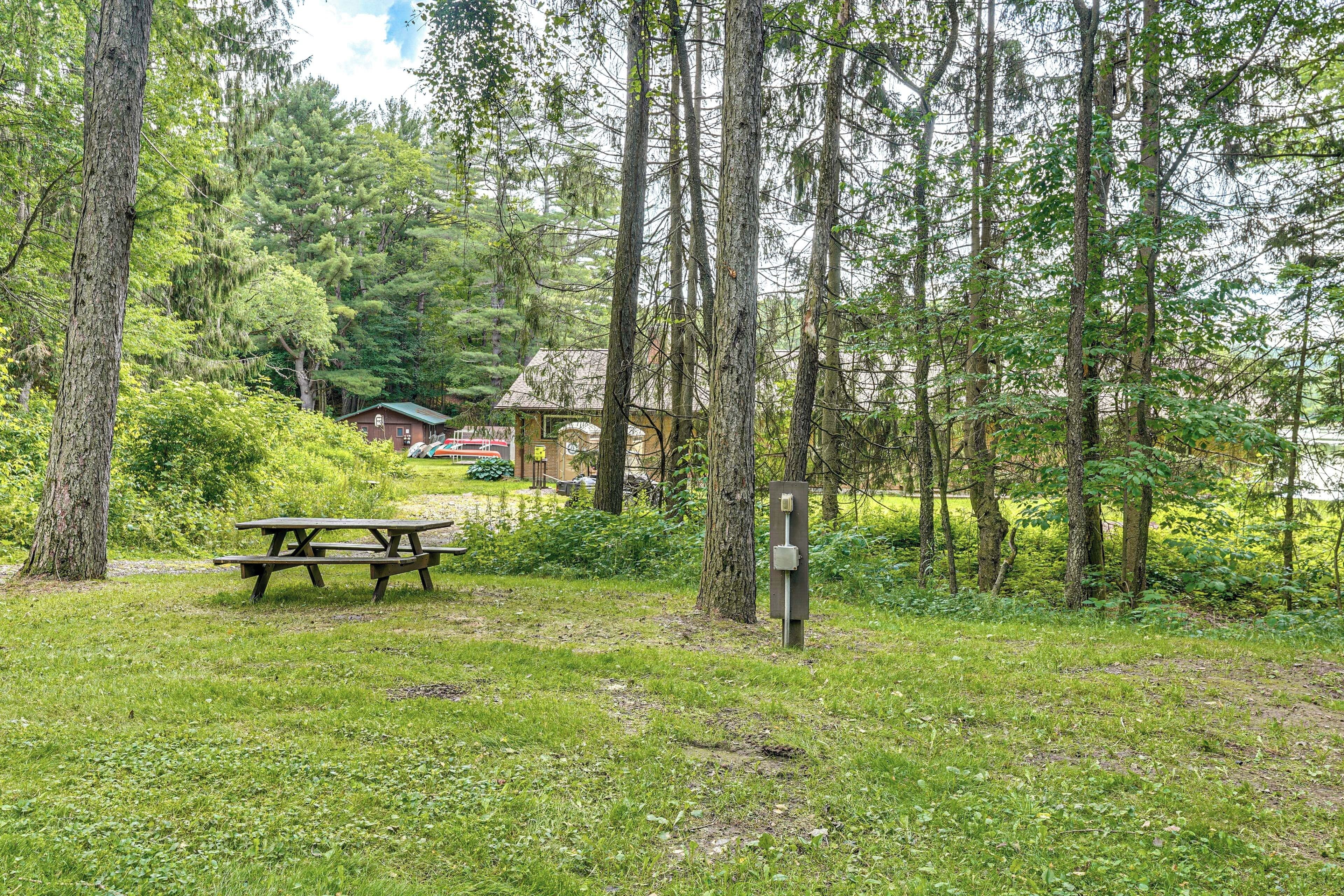 A picnic table in a forested area with a cabin in the background.