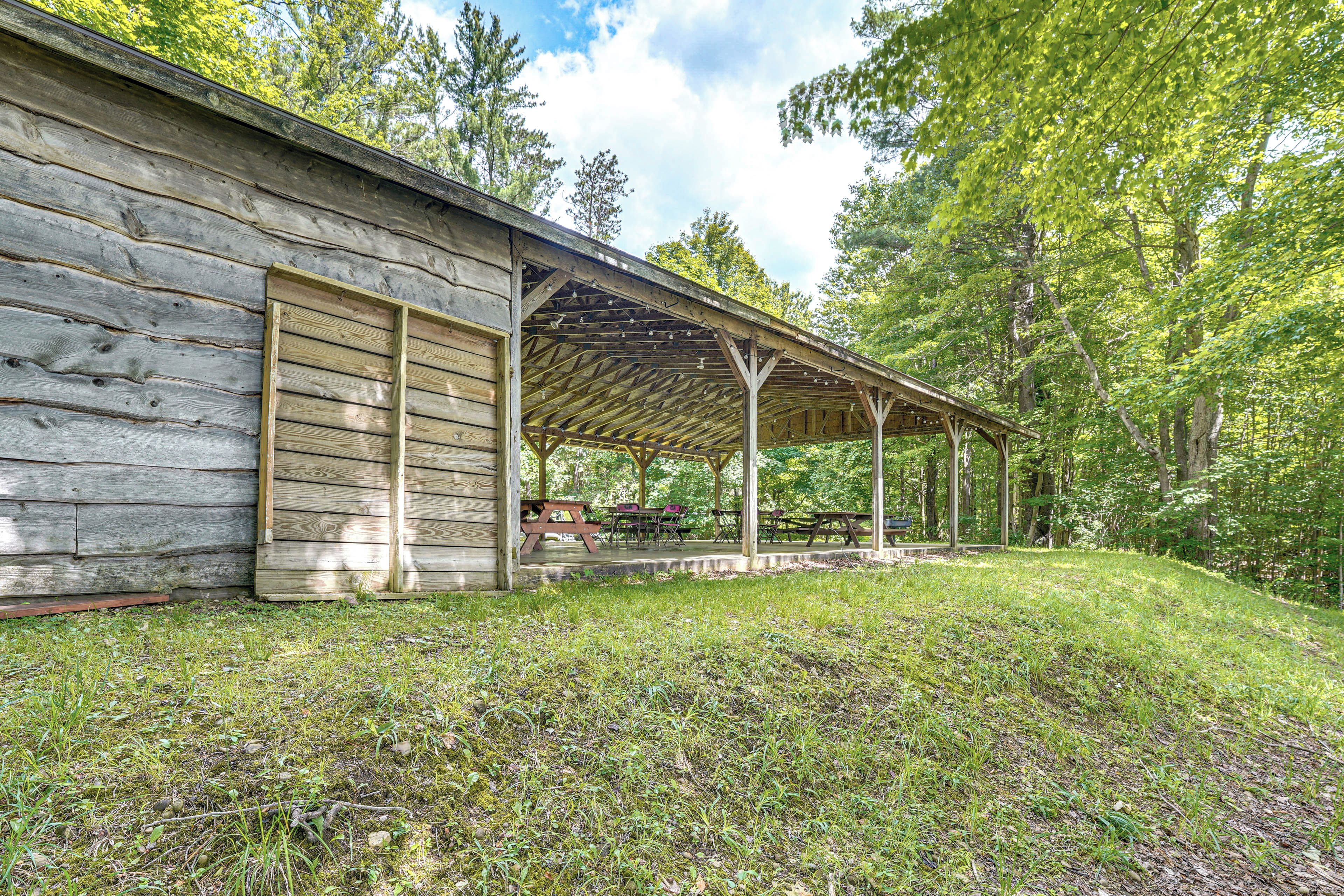 A rustic wooden cabin with a covered porch and picnic tables.