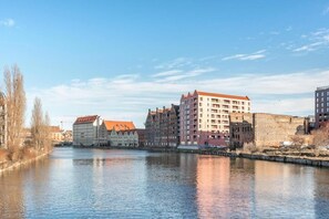 A river with buildings along the banks, including a mix of modern and traditional architecture. - Nº 65A | Private Jacuzzi | AC | Pool, SPA & Gym (Gdańsk)