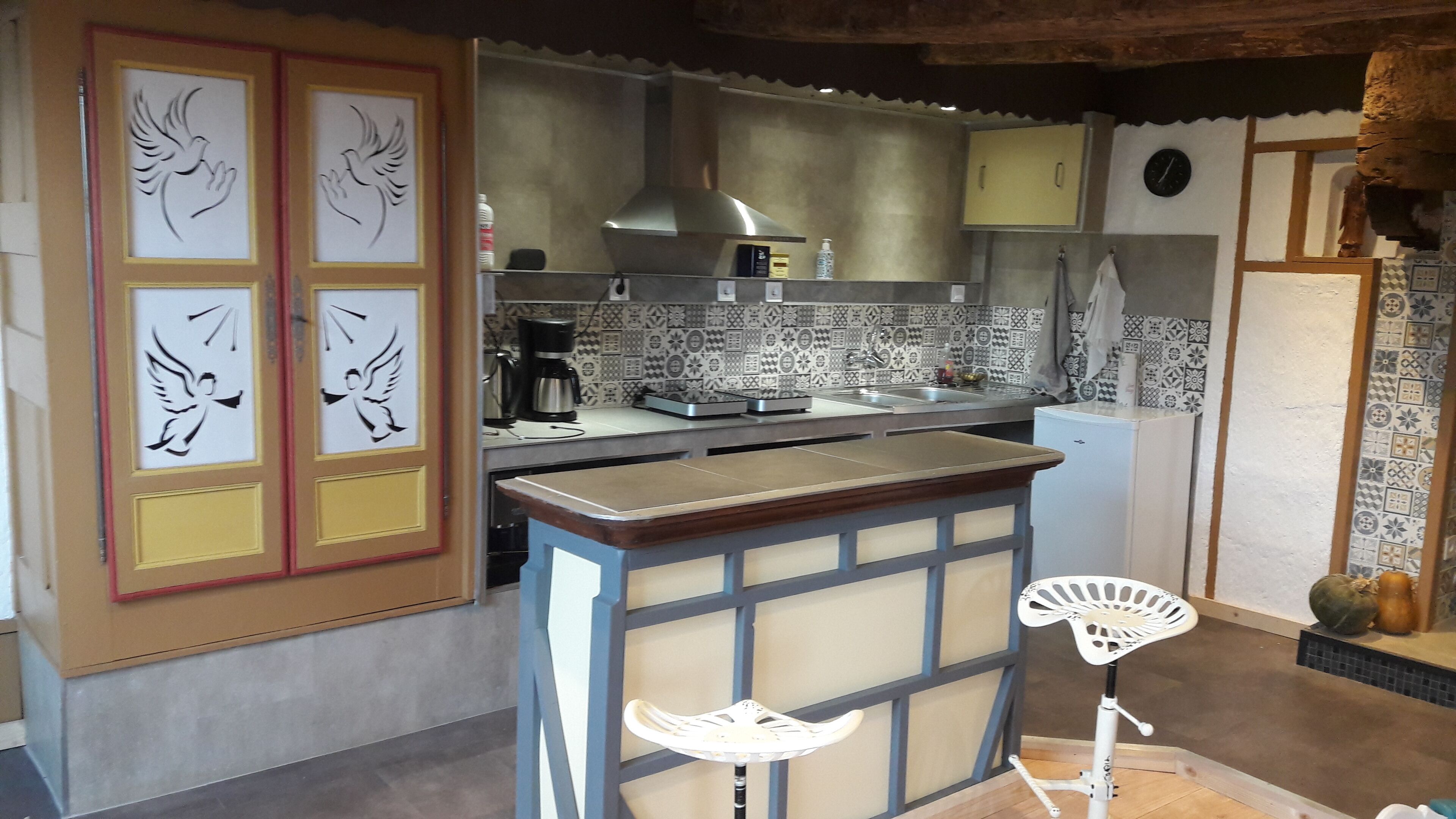 A kitchen with a tiled backsplash, a coffee machine, and a refrigerator.