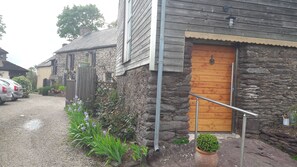 A rustic building with a wooden door, stone walls, and a gravel driveway. - Brocéliande East Vacation Rental (Iffendic)