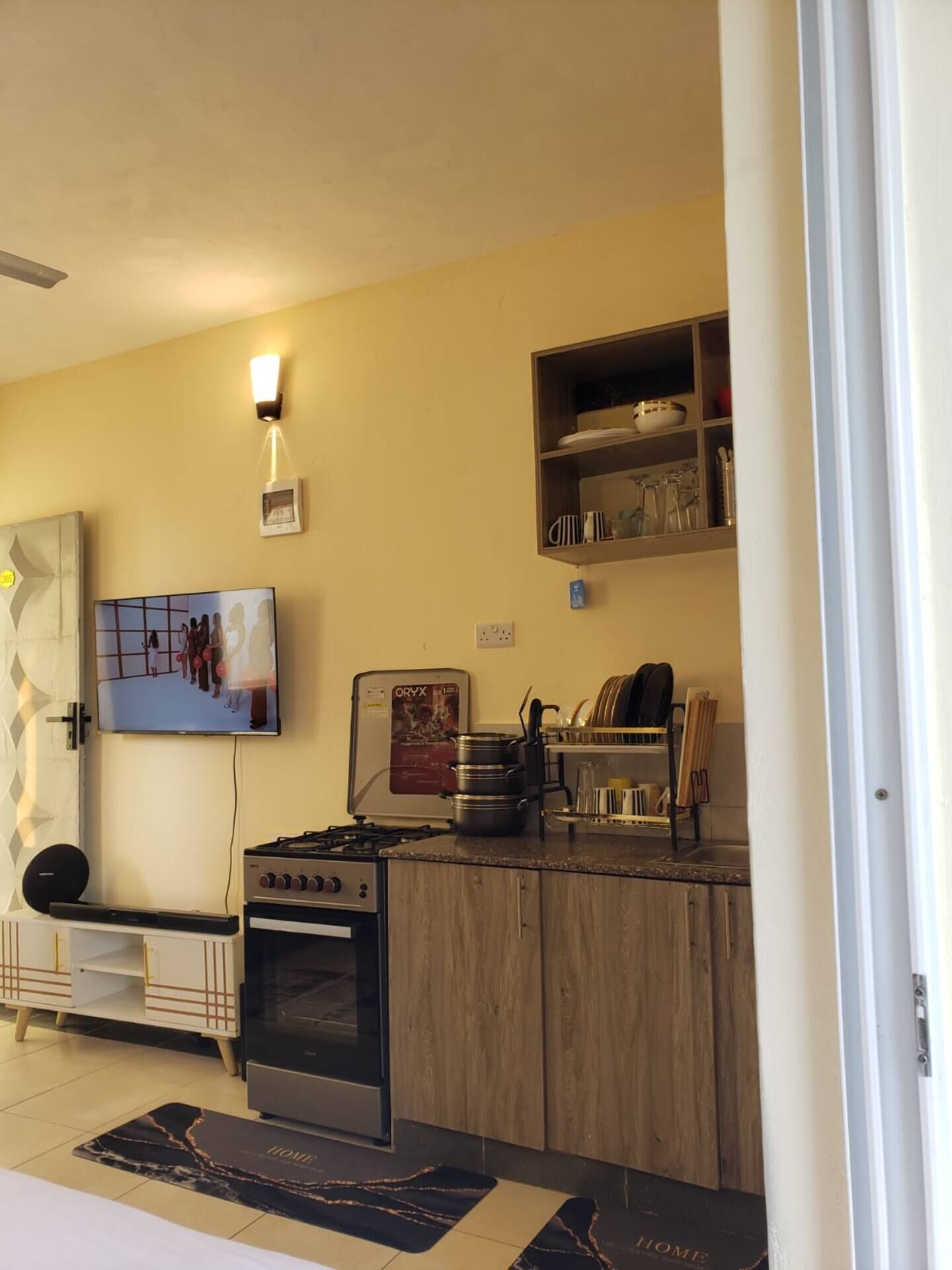 A kitchen with a gas stove, oven, and a wall-mounted TV.