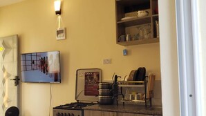Une cuisine équipée d’une cuisinière à gaz, d’un four et d’un téléviseur fixé au mur.