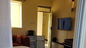 Une chambre d’hôtel équipée d’un lit, d’une télévision, d’un four à micro-ondes et d’une petite kitchenette.