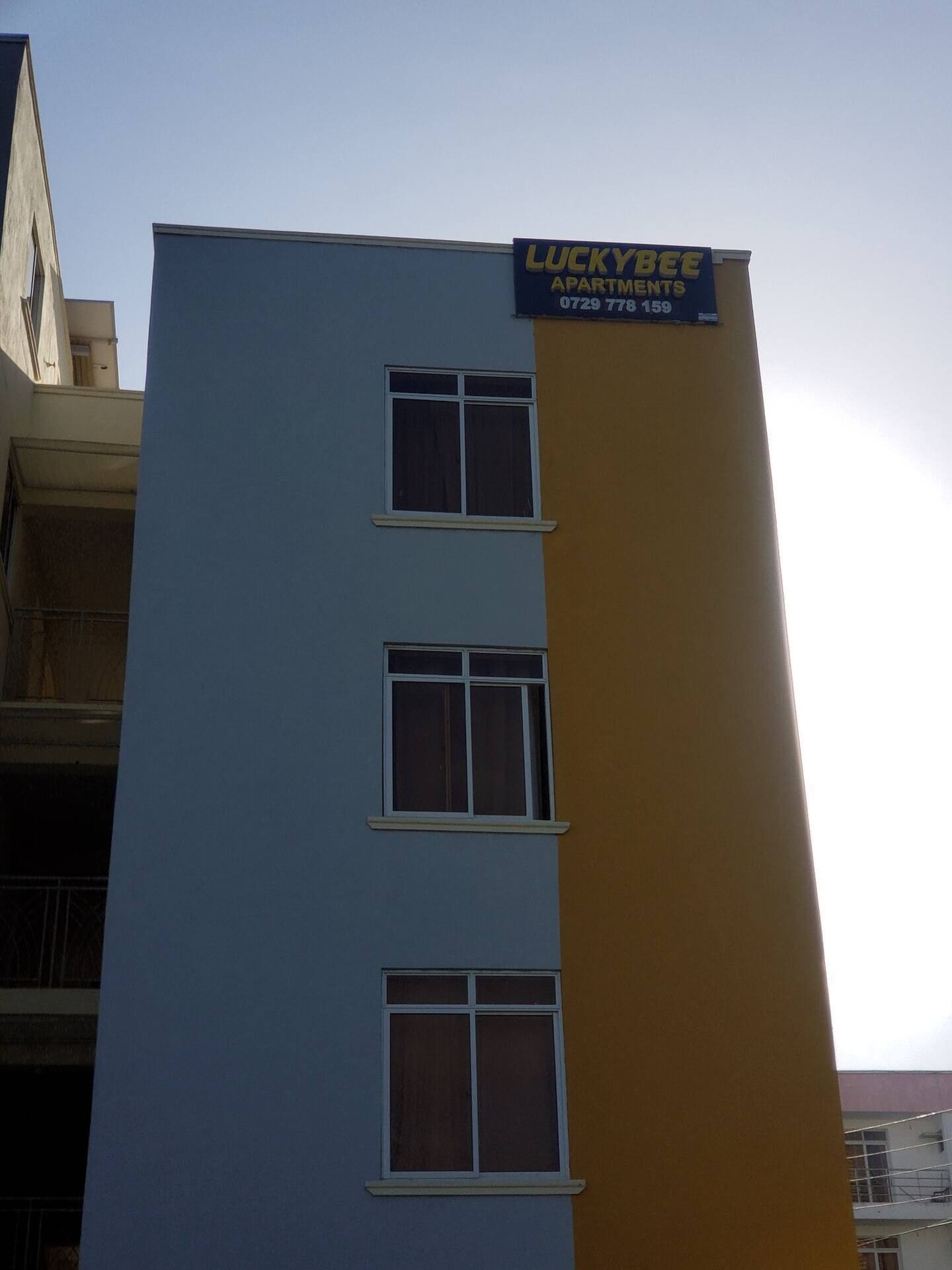 A multi-story building with a sign for 'Luckybee Apartments' on the side.