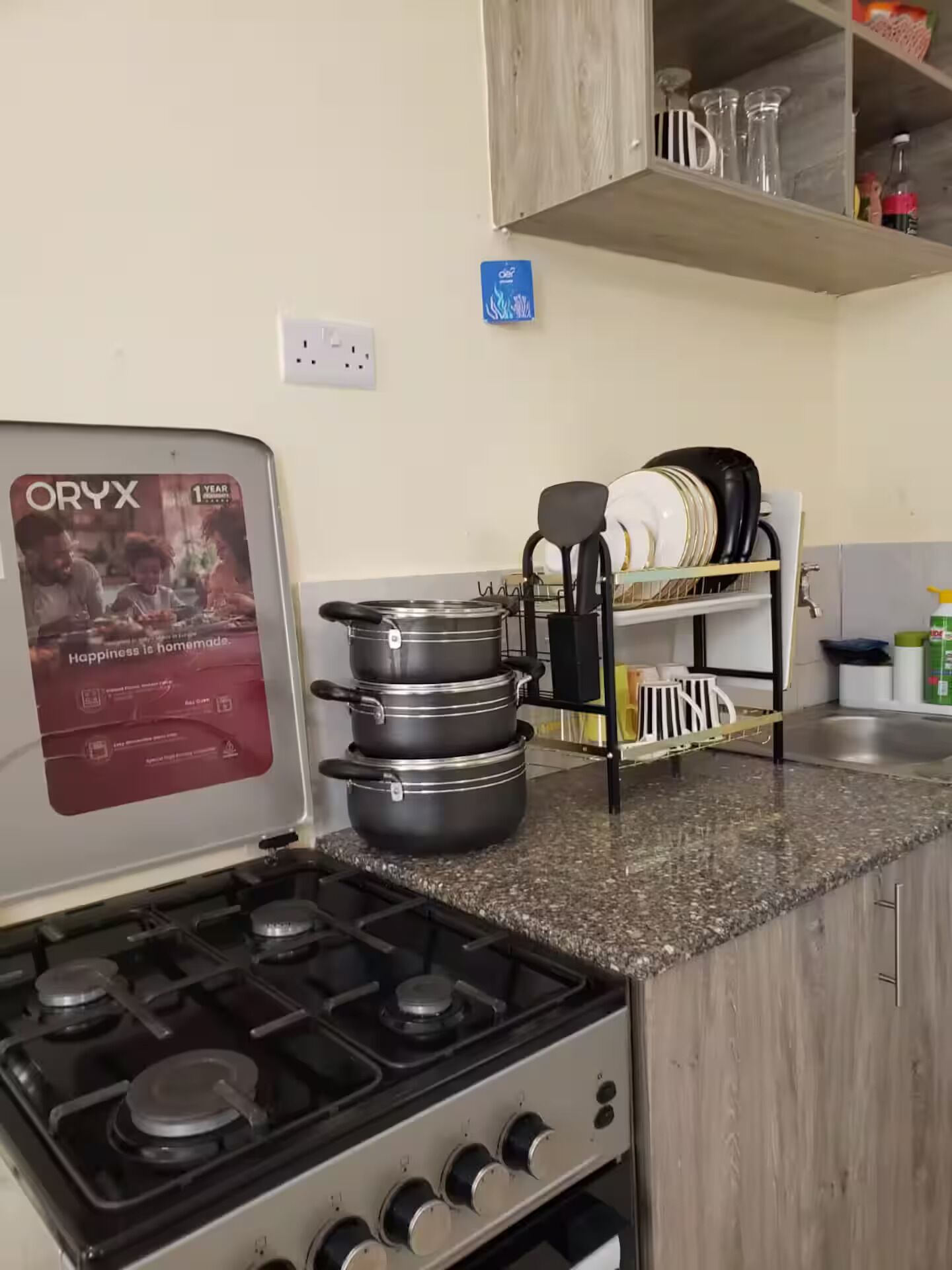 Une cuisine équipée d’une cuisinière à gaz, de casseroles, d’une machine à café et d’un égouttoir à vaisselle.