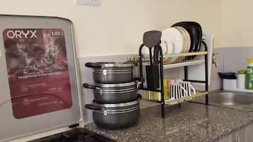 Une cuisine équipée d’une cuisinière à gaz, de casseroles, d’une machine à café et d’un égouttoir à vaisselle.