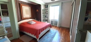 A bedroom with a bed, a bookshelf, and a window.