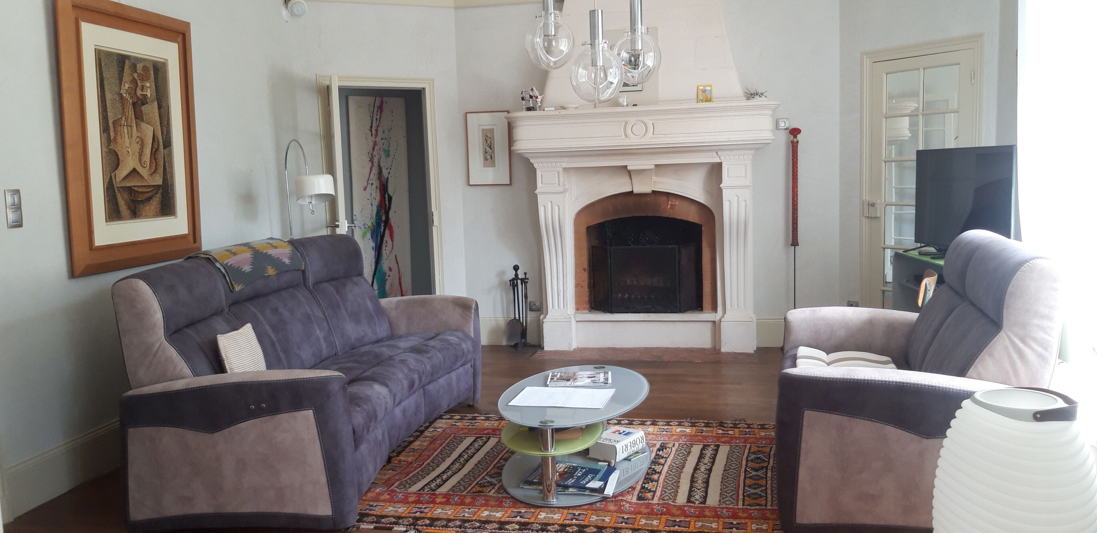 Una sala de estar con chimenea, dos sofás, una mesa de centro y un televisor.