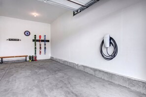 A clean, modern indoor space with a bench, skis, and a Tesla charging station. - Grill-Mnt Views-Private Hot Tub-King Bed-Sleeps 12 | Moose Mgmt 1132 (Park City)