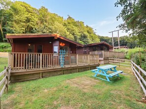A wooden cabin with a deck and a picnic table. - Seagull Lodge (Ilfracombe)
