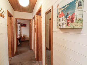 A hallway with wooden doors and a painting of houses on the wall. - Seagull Lodge (Ilfracombe)