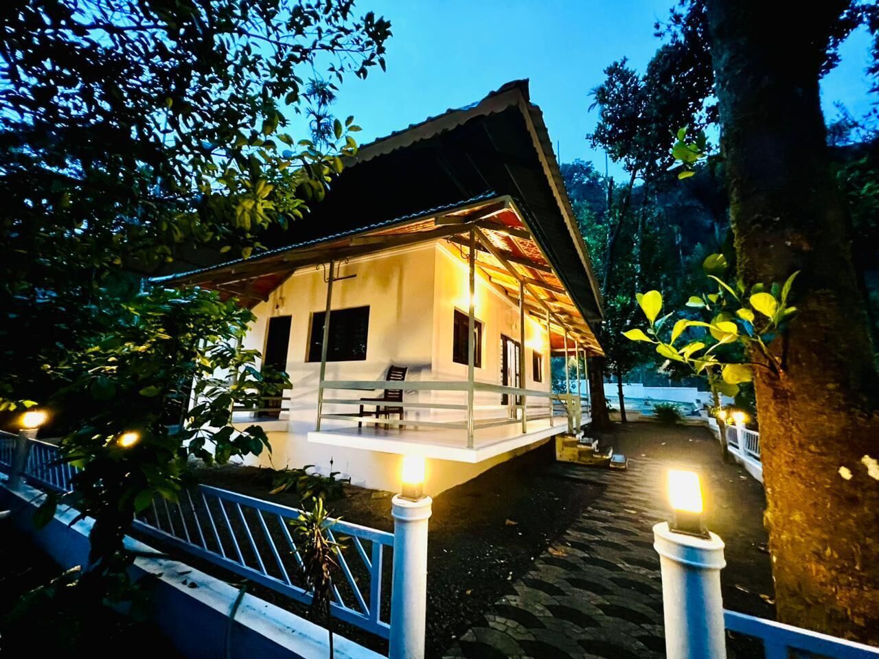 A two-story building with a balcony, surrounded by trees and a wooden deck.