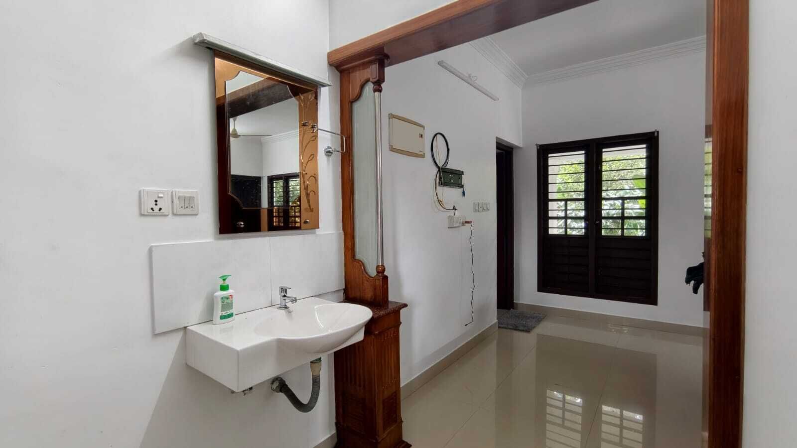 A bathroom with a white sink, mirror, and wooden door frame.