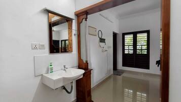 A bathroom with a white sink, mirror, and wooden door frame.