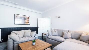 A modern living room with two sofas, a coffee table, a framed picture, and a door.