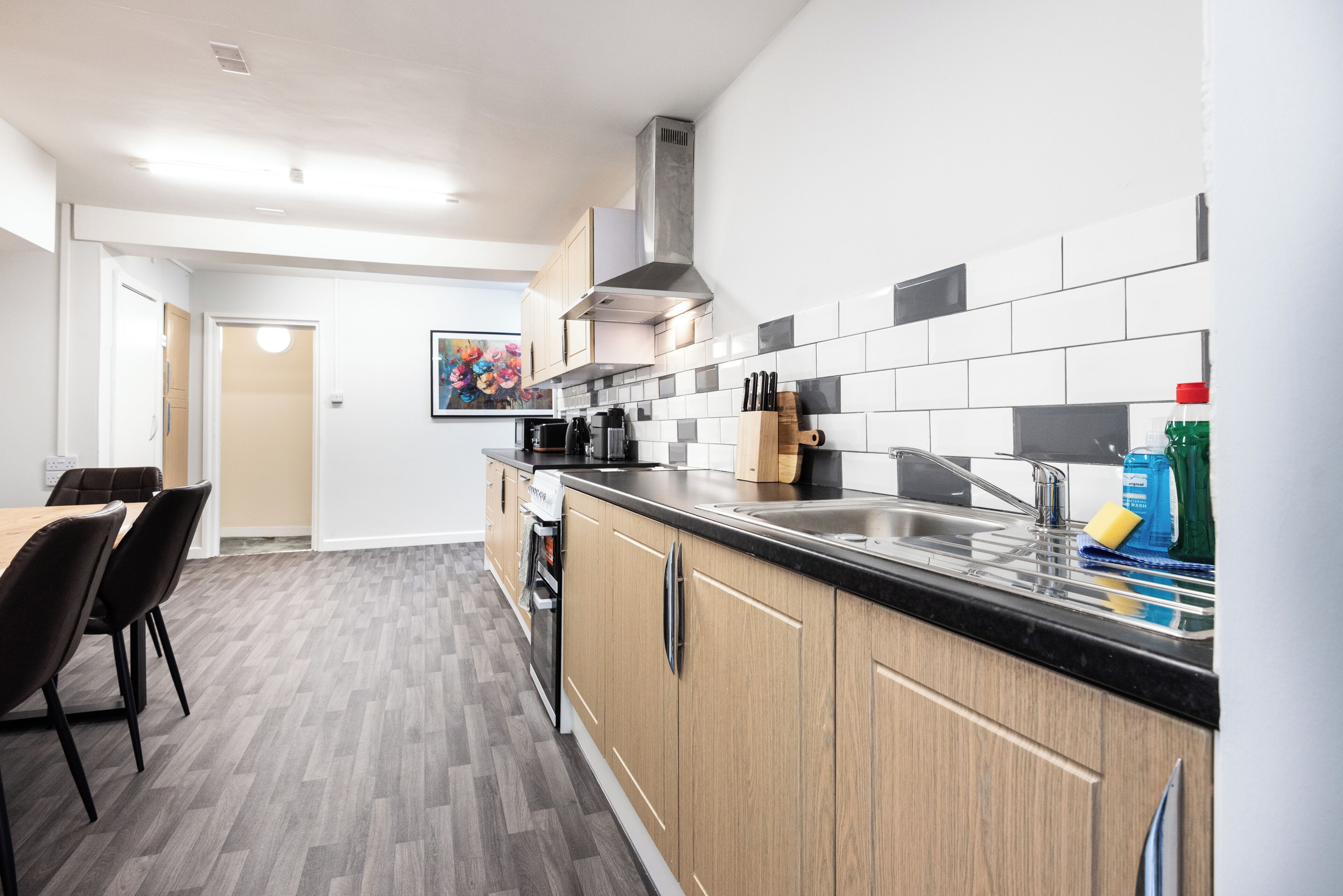 A modern kitchen with a black countertop, wooden cabinets, and a stainless steel sink.