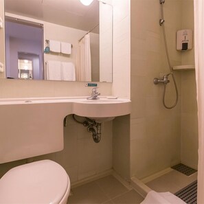 A bathroom with a white sink, a toilet, a shower, and a mirror. - Jinjiang Inn (Qingdao)
