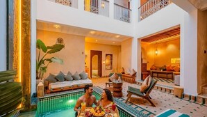 A pool area with a dining table, lounge chairs, and a sofa. - Luxury Private Riad Taj 2Min Jemaa Lefna (Marrakech)