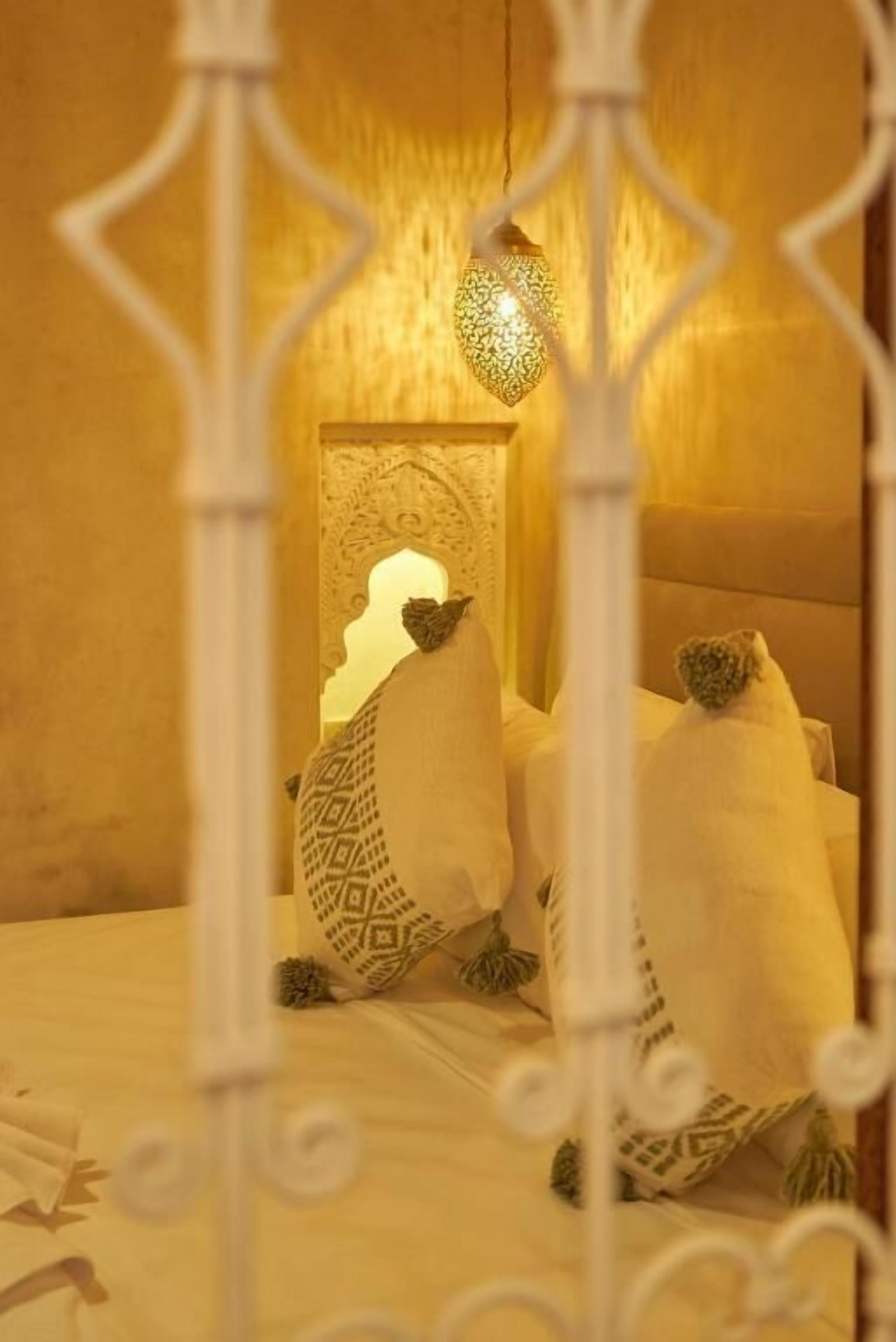 A bed with patterned pillows and a hanging light fixture.