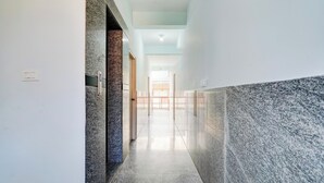 A corridor with a marble floor, a door with a handle, and a light switch on the wall. - Super Collection O Uttarahalli (Bangalore)
