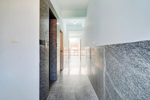 A corridor with a marble floor, a door with a handle, and a light switch on the wall. - Super Collection O Uttarahalli (Bangalore)