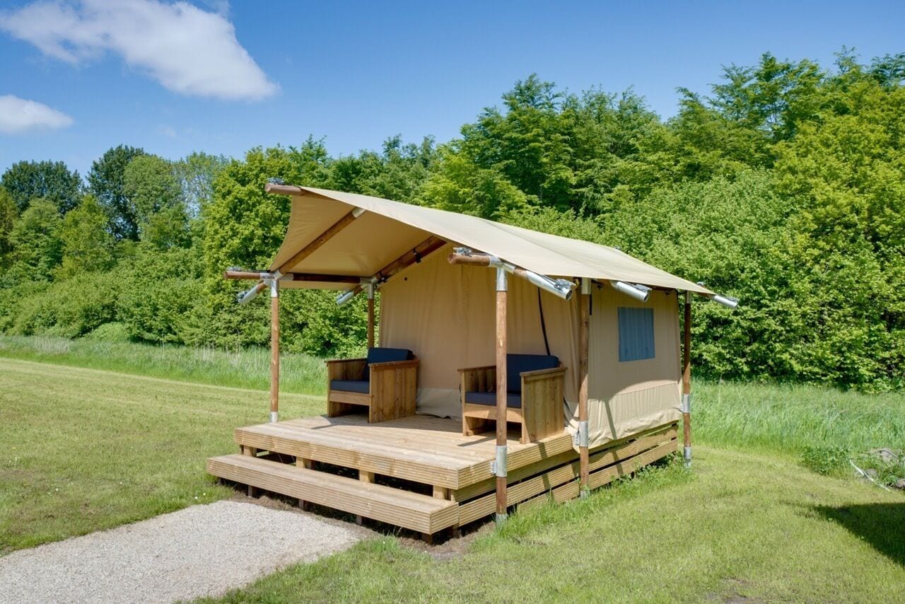 A single-room tent with a wooden deck, two seating areas, and a canopy.