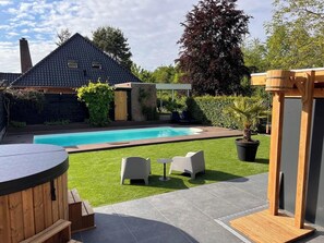 A backyard with a swimming pool, a hot tub, and outdoor seating.