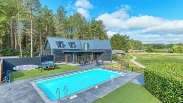 Une maison moderne dotée d’une piscine, d’un espace salon extérieur et offrant une vue sur un terrain de golf.