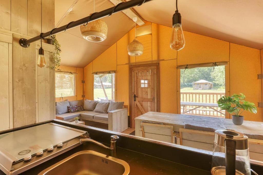 Un intérieur de chalet chaleureux comprenant un coin cuisine, un espace repas et un coin salon avec vue sur l’extérieur.
