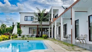 Une maison moderne dotée d’une piscine, d’un espace salon extérieur et d’un jardin.