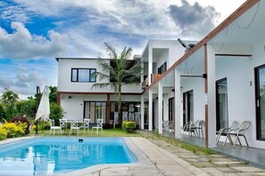 Una casa moderna con piscina, mobiliario de exterior y jardín.
