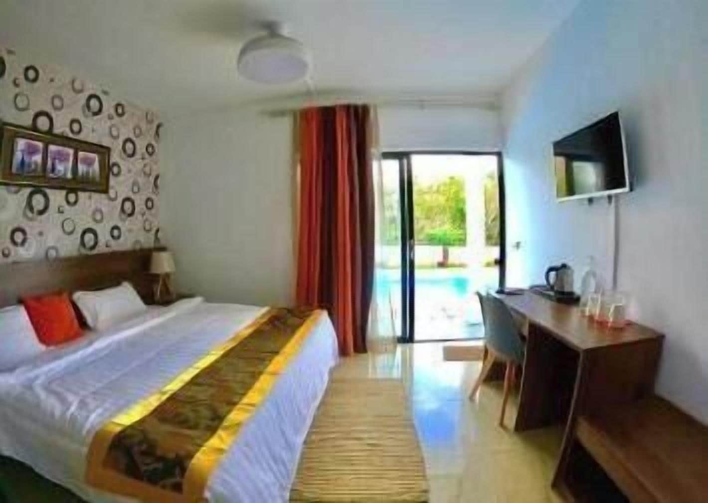 Una habitación de hotel con cama, escritorio, televisor y vistas al exterior.