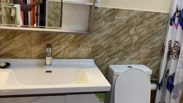 Une salle de bain avec un lavabo blanc, des toilettes, un miroir et un rideau de douche.