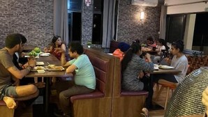 Un restaurant avec des banquettes et des tables, des ventilateurs de plafond et des murs en briques.