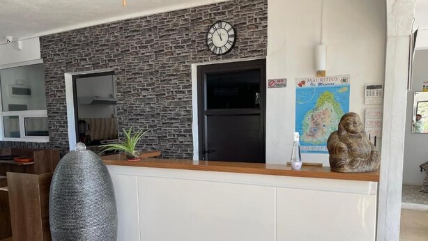 Un comptoir d’accueil avec une horloge, une carte et une statue.