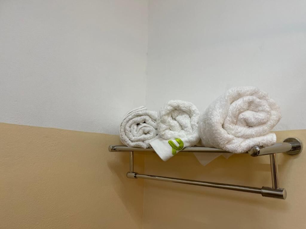 Un porte-serviettes avec trois serviettes soigneusement pliées, appuyées contre un mur.