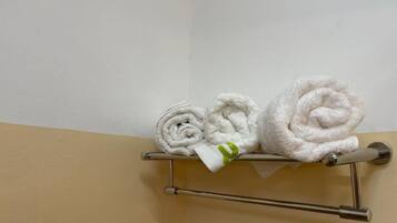 Un porte-serviettes avec trois serviettes soigneusement pliées, appuyées contre un mur.