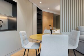 Un comedor moderno con una mesa redonda, dos sillas y una botella de vino.