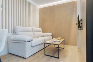 A modern living room with a sofa, a coffee table, and a wall-mounted TV.