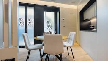 A modern dining area with a round table, four chairs, and a glass of wine.