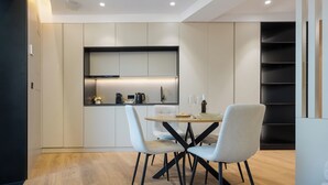A modern kitchen with built-in appliances, a dining table with chairs, and a bookshelf. - Panther Home Puerta Osario (Casco Antiguo)