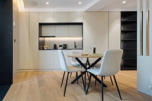 Una cocina moderna con electrodomésticos integrados, una mesa de comedor con sillas y una estantería.