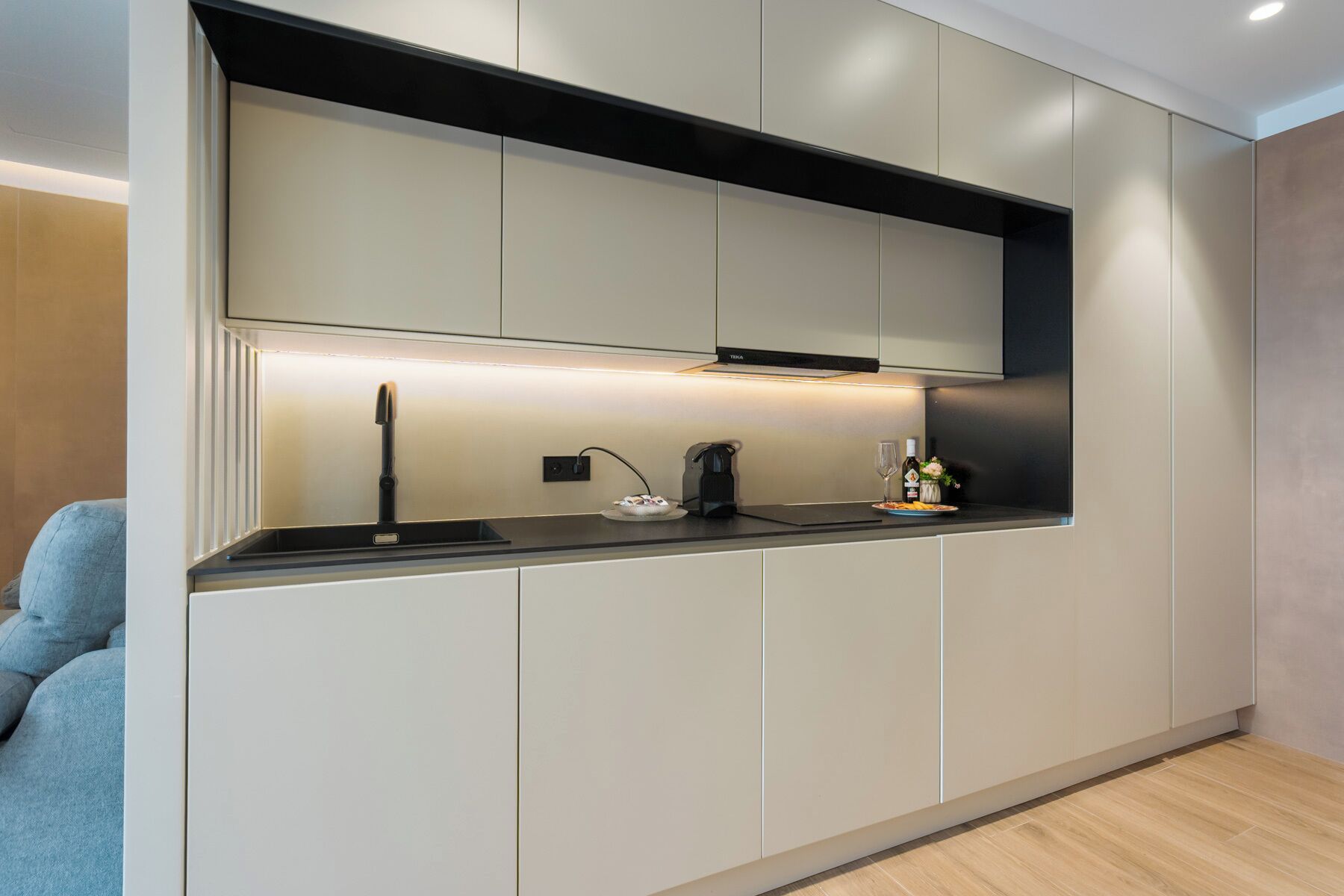 Una cocina moderna con horno integrado, cafetera y una botella de vino sobre la encimera.