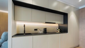 A modern kitchen with a built-in oven, a coffee machine, and a wine bottle on the counter. - Panther Home Puerta Osario (Casco Antiguo)