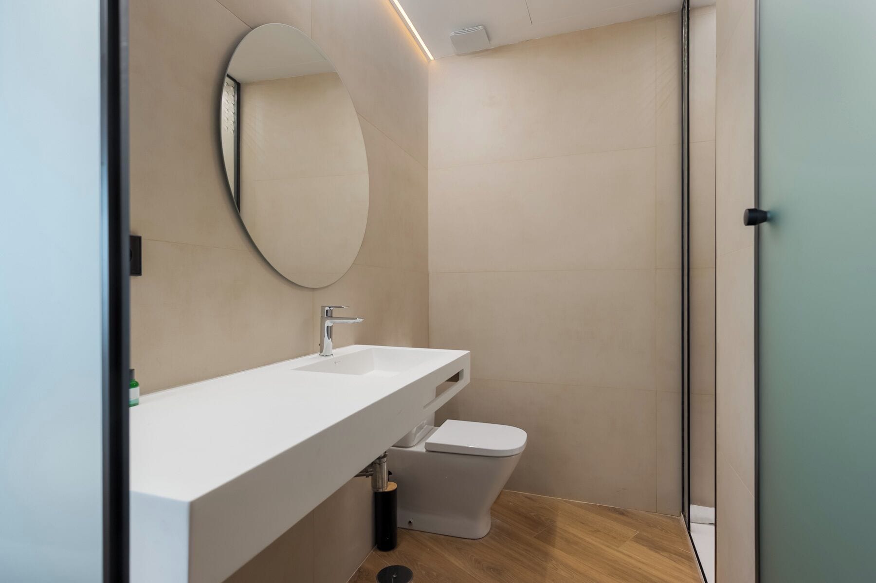 A modern bathroom with a white sink, a toilet, and a mirror.